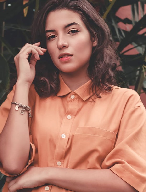 A woman wearing an orangish color shirt
and looking at the camera