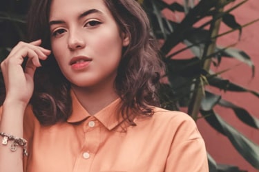 A woman wearing an orangish color shirt
and looking at the camera